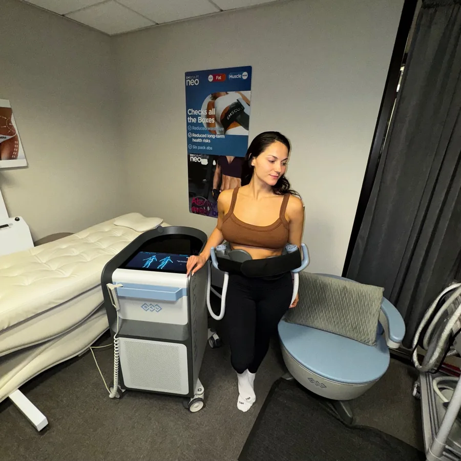 Person standing with abdominal treatment applicators beside body-treatment equipment