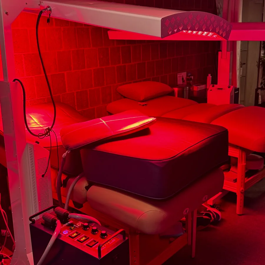 Illuminated red light panels surrounding a treatment bed at Rescu